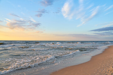 Sunset on Baltic Sea white pastel color sky and rough sea.