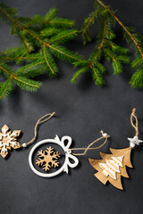 Coniferous branches on dark background top view. Wooden New Year's handmade toys lie in row.