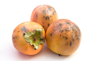 Persimmons with hail wounds from a storm on neutral background and copy space