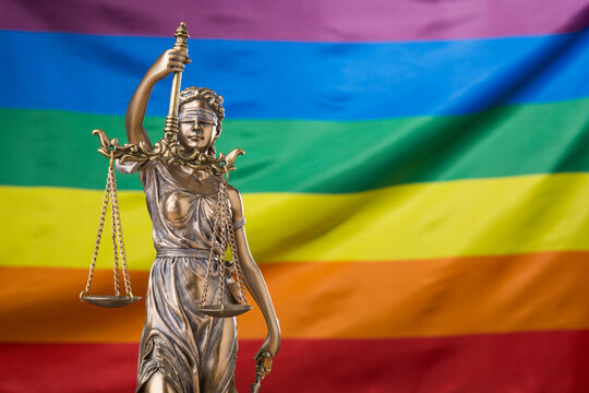 The Blindfolded Goddess Of Justice Themis Or Justitia Against The Rainbow Flag Of LGBT Community, As A LGBT Social Issues Concept