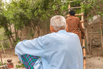the old man is sitting and watching Gardner while he is working