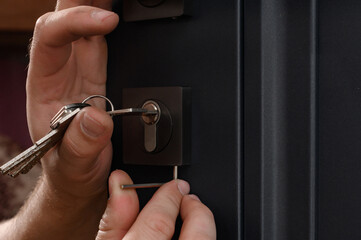 Installation of a door lock, a carpenter installs a door lock in a door, work close-up.