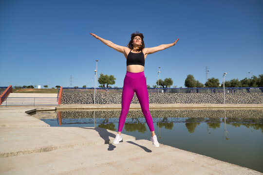 Mature woman in sportswear jumping in the air happy in an outdoor park. Fitness concept, maturity, relax, happiness, jumping.