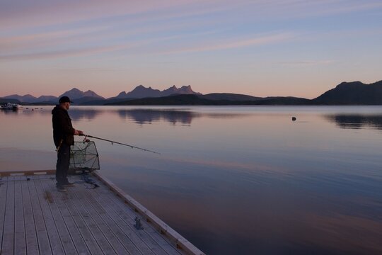 Silhouette of a fisherman fishing in sunset time on the open sea