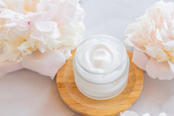 Fototapeta na wymiar Top view of jar with face cream and pink peony flowers. Natural organic cosmetics concept