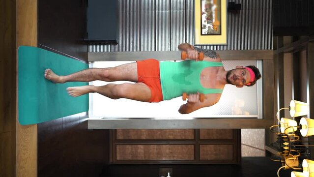 Freaky crazy gay man lifting DUMBBELLS and pumping muscles, funny funny guy fooling around, close-up of a guy in a blue t-shirt. Vertical video meme for social networks, funny and sexy