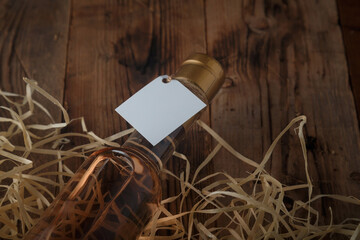 250 ml bottle of pink wine with blank label lying on wooden shavings, wooden table. Alcohol drink. Copy space