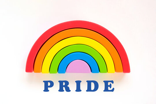 Wooden rainbow and Pride lettering on a white background. The rainbow toy puzzle. LGBT flag gay pride community, equal rights movement and gender equality life concept. Flat lay, top view, copy space