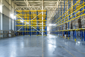 Interior of a modern warehouse storage of retail shop with pallet truck near shelves. Rows of steel shelves and racks