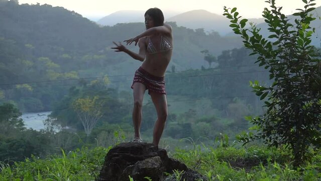 Elegant Asian girl with painted body performing an extatic dance in the tropical valley at sunset time. Mountains Oaxaca