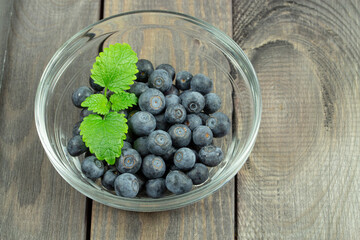 Some blueberries in a small transparent bowl with mint leaves close-up