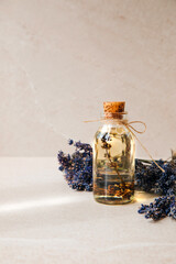 Lavender oil on light stone background with lavender flowers. Front view