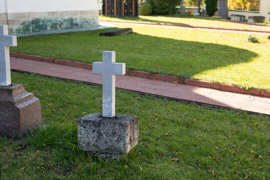 White even cross made of marble on the green lawn of the cemetery