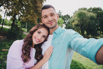 Photo of two idyllic positive people take selfie record video cuddle embrace support walk park outdoors