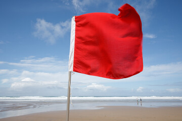 Red flag on the Beach. A red flag flies in the wind on a windy but sunny summer's day, warning...