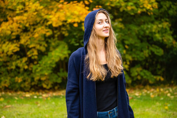 pretty smiling blond female wearing long hoodie with hood on her head looking at the camera,...