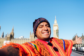Traveler man with peruvian colorful poncho in front of Big Ben Tower taking memory pic