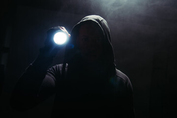 Silhouette of hooligan holding flashlight on black background with smoke - obrazy, fototapety, plakaty