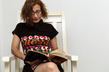 Latin American woman sitting on a chair at home reading a book.