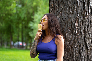 Beautiful girl in a purple top eats ice cream in the park