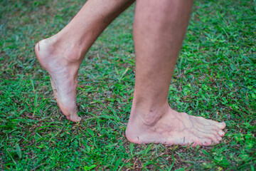 Bare feet moving forward in wet grass. Concept, connection with the earth. horizontal.
