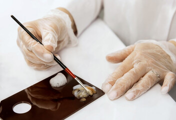 A woman mixes paints on a palette. Close-up. Shallow depth of field