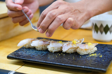 rofessional sushi chef carefully add final touch with confident and dedication to his perfect sushi. Precision and Finesse at its best practice to achieve top performance in business..