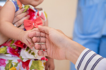 Doctor gently holding the girl's hand in the hospital.