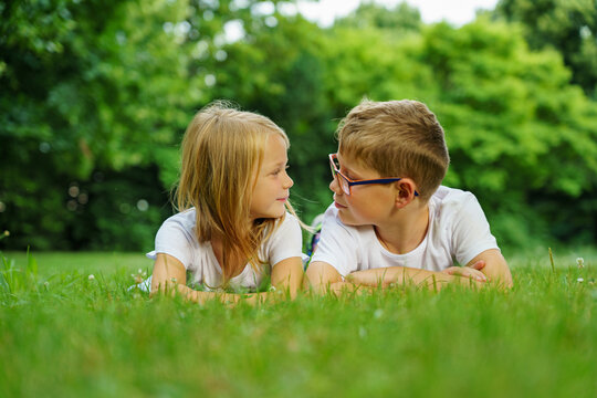 Children Lying On The Green Grass In The Park. The Interaction Of The Children