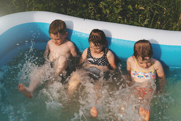 Cheerful happy children in the pool. Friends spend summer leisure together on a hot sunny day