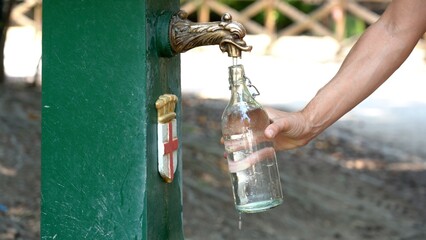 fill the thermal bottle with water at the fountain in Milan - record heat hot day  in summer with...