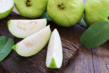Three slices of green guava fruit with leaf on rough old wood and wooden table.