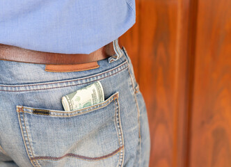 Close up blue jeans trousers pocket with dollar bills.