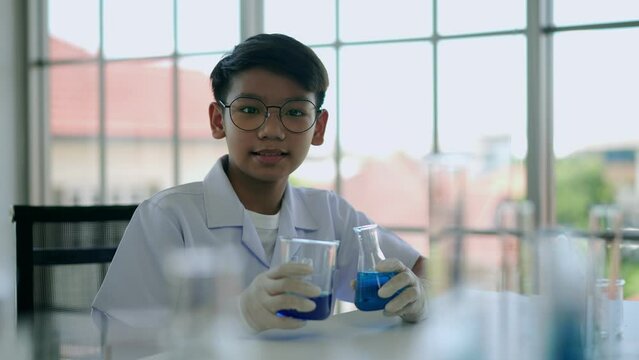 Little boy researches blue liquid in chemistry lesson at laboratory