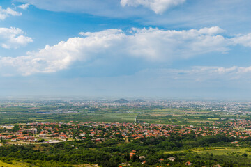 Town Plovdiv with houses and fields against backdrop of Rhodope Mountains and hills covered with forests and cloudy sky