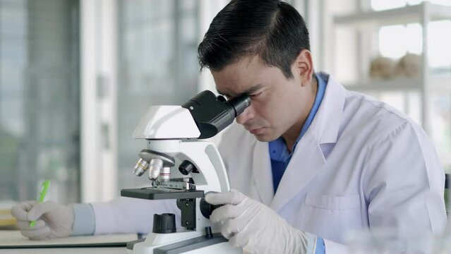 Young scientist man looking through microscope in laboratory