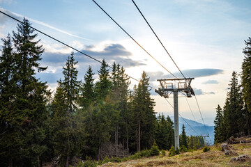 Lift with cable passes between spruce forest on peak against backdrop of mountain ranges of Rhodope...