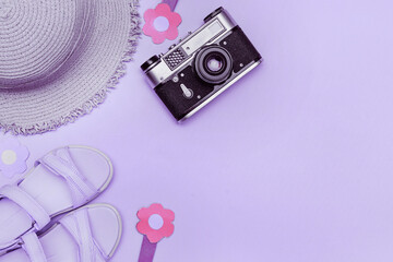 Sea beach flat lay set. Purple sun hat, women's sandals, flowers, retro camera on lavender...