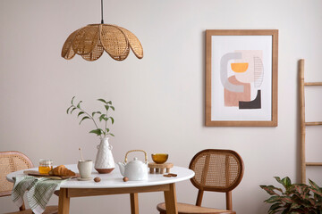 The stylish dining room with round table, rattan chair, wooden commode, pock up poster and kitchen...