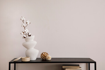 The stylish composition of minimalistic interior with copy space. White vase with dried flowers and stylish accessories. Beige wall. Home decor. Template.
