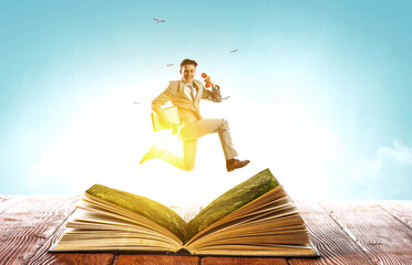 Businessman in suit running on top of a book