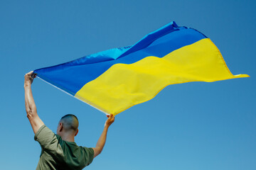 man waving the ukrainian flag on the sky