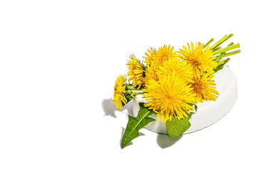 Dandelion flowers bouquet on trendy stand isolated on a white background. Springtime concept