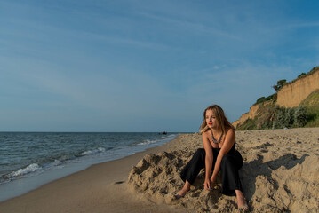 Woman wearing black dress walking on beach. See view