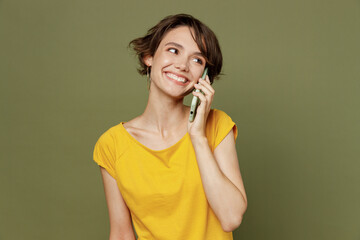 Young happy woman she 20s wear yellow t-shirt talk speak on mobile cell phone conducting pleasant...