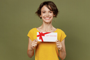 Fototapeta na wymiar Young smiling cheerful fun happy woman she 20s wear yellow t-shirt hold gift certificate coupon voucher card for store isolated on plain olive green khaki background studio. People lifestyle concept.