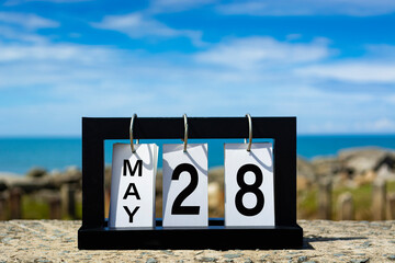 May 28 calendar date text on wooden frame with blurred background of ocean.