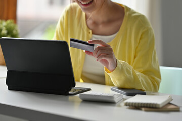 Close up of Asian women holding a credit card and looking on tablet for purchasing online
