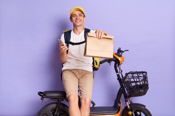 Horizontal shot of satisfied delighted courier man wearing white t shirt and cap delivering parcels...