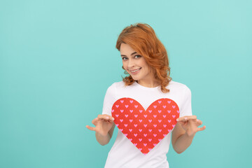 cheerful redhead girl hold red heart on blue background